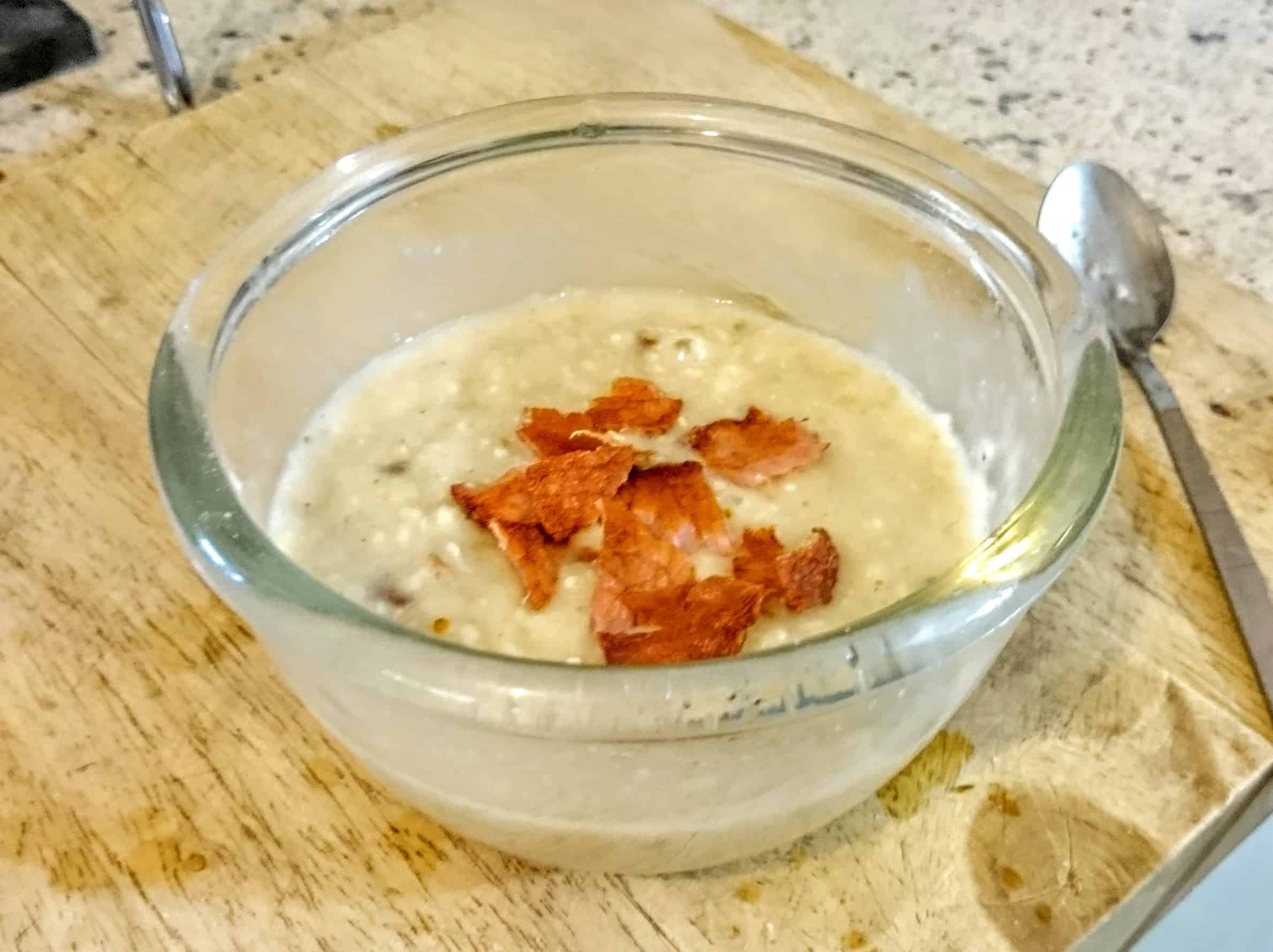 Bacon and porridge in a glass bowl on chopping board