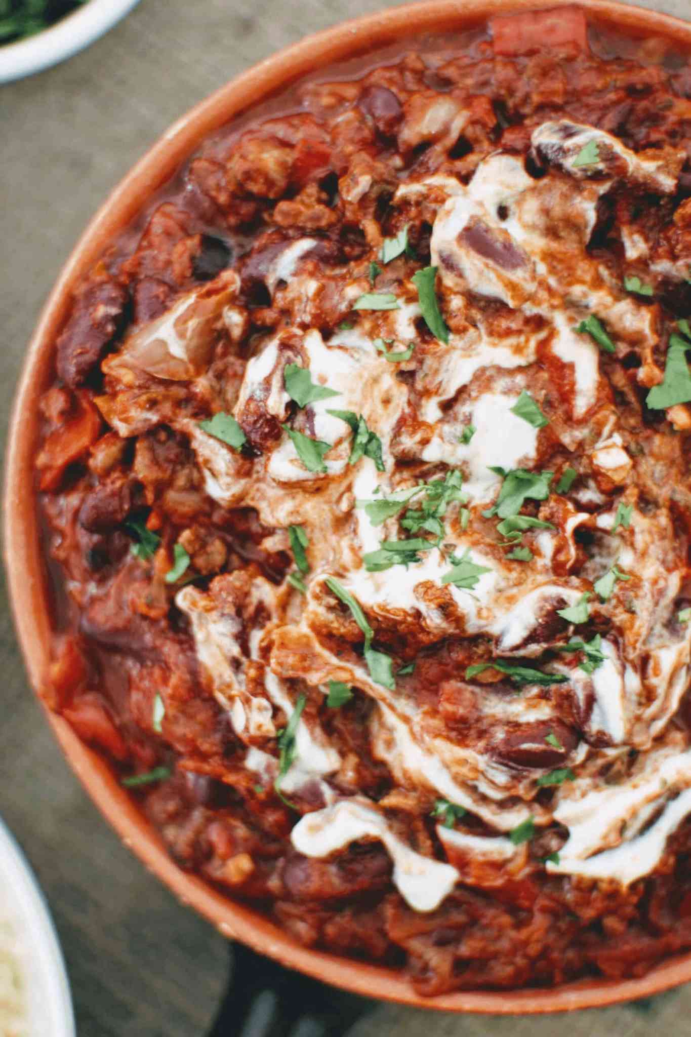 close up of minced beef in a rich tomato sauce with kidney beans, cream and fresh parsley