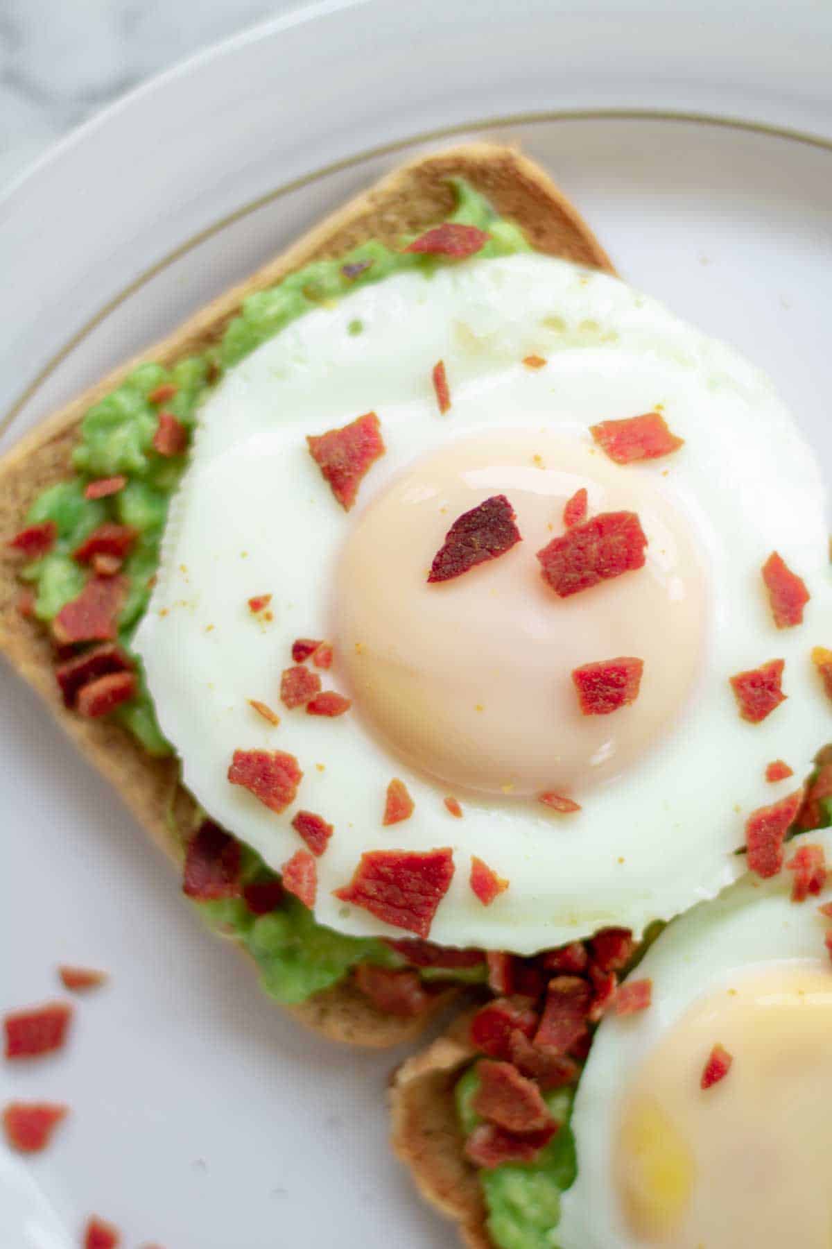 Close up of egg bacon and smashed avocado on toast