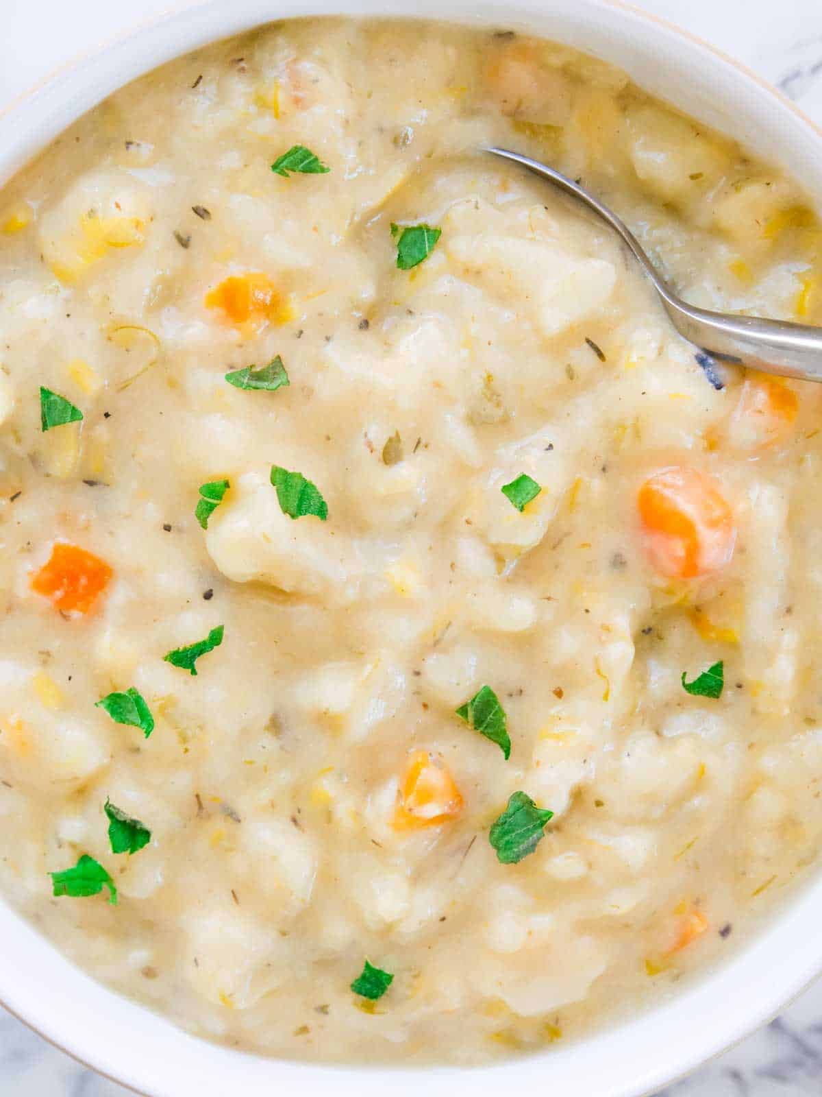 Close up of creamy cheesy potato and carrot soup in a white natural canvas Denby bowl