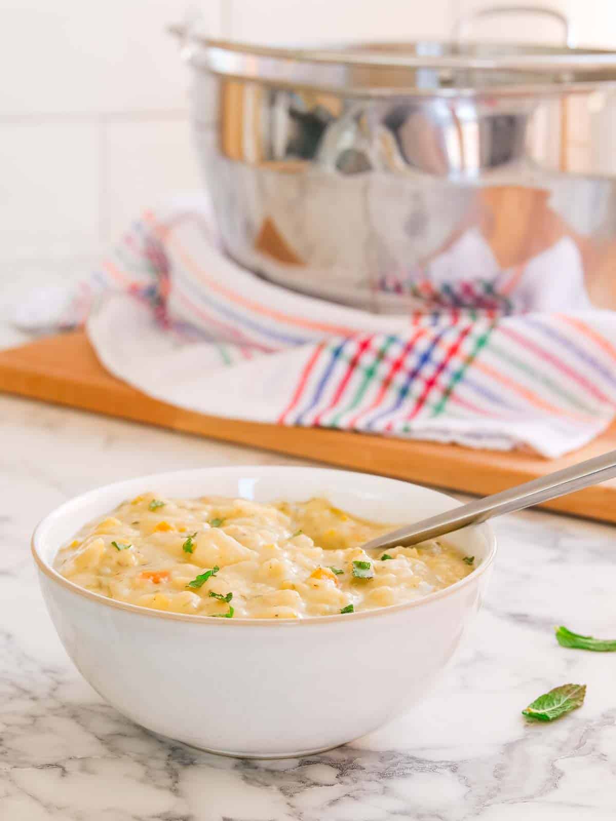 Serving chunky and creamy cheese and potato soup from a large jam pan