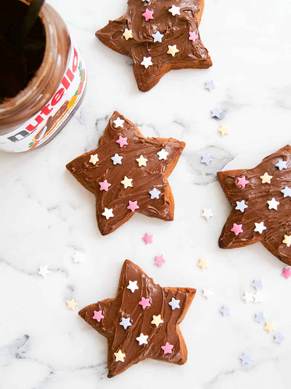star shaped chocolate chip cookies baked and decorated with Nutella and star icing sugar sprinkles