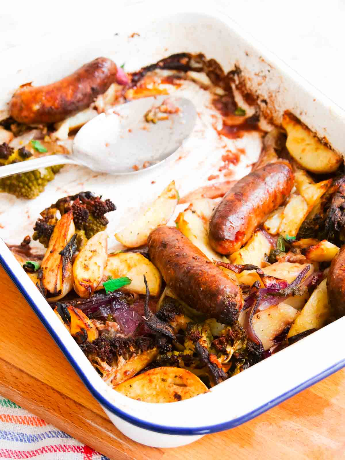serving a sausage tray bake with caramelised veggies