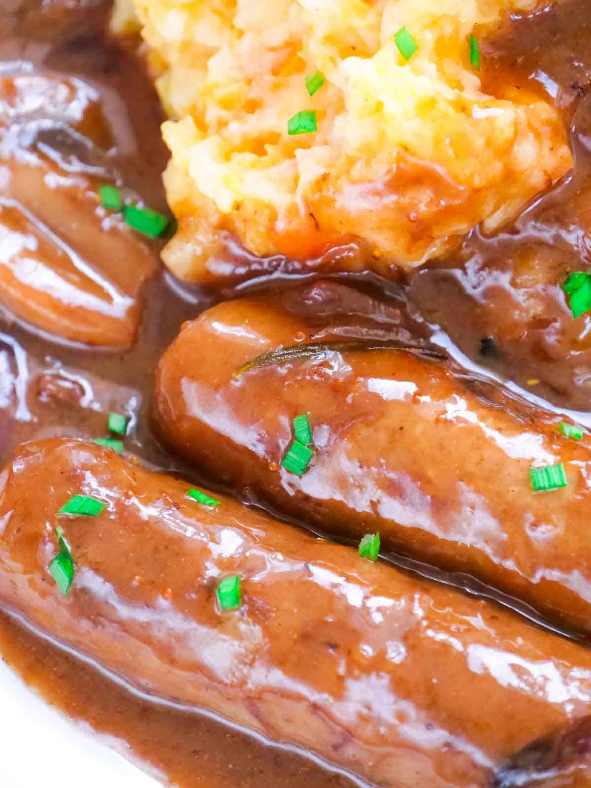 Glossy close up of rich bangers and Colcannon potato and mixed root veg mash