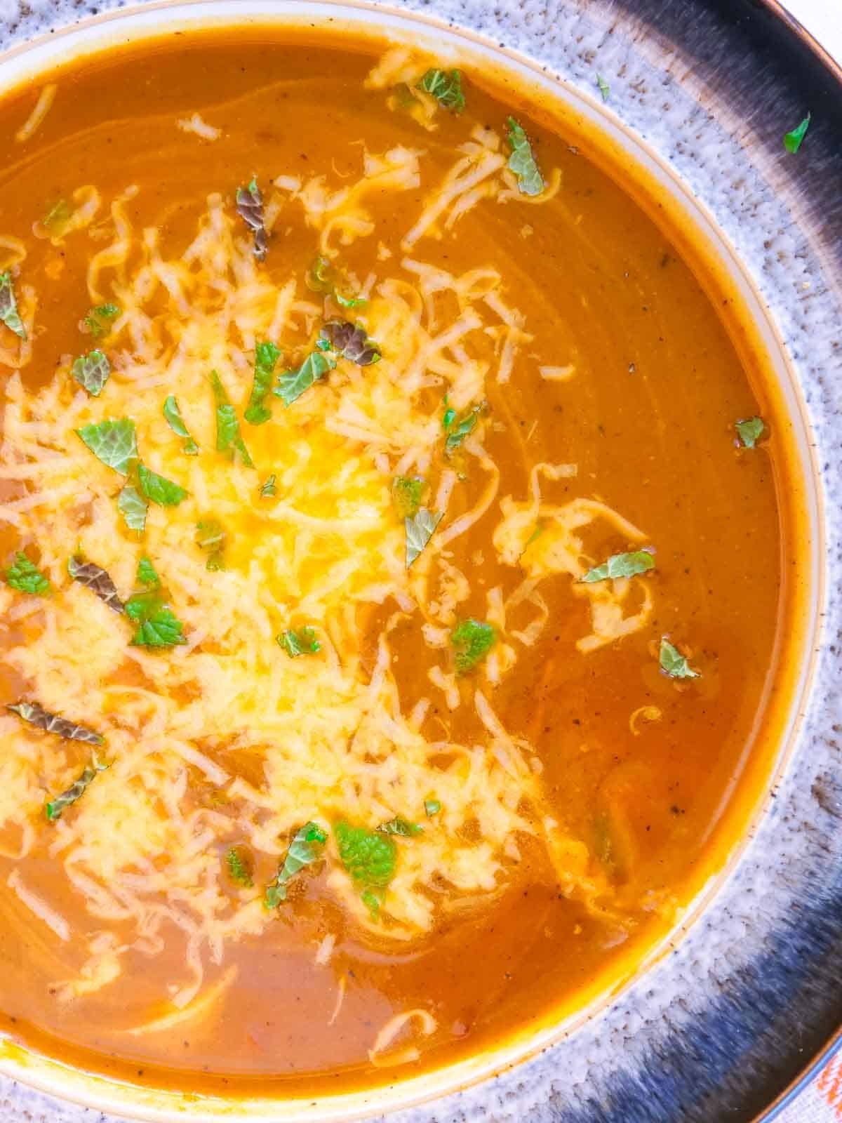 chopped lemon balm and grated cheese sprinkled on spicy butternut soup