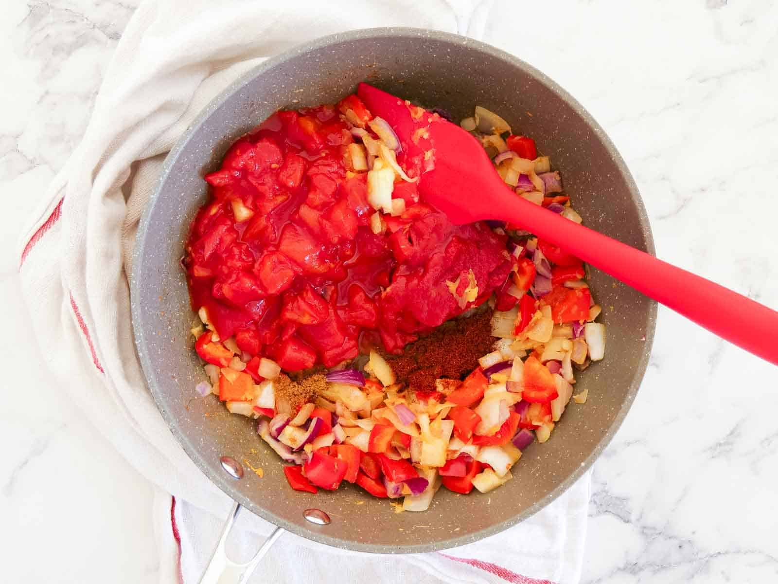 Sauteed vegetables on a marble counter with tinned tomatoes, puree and chilli spices