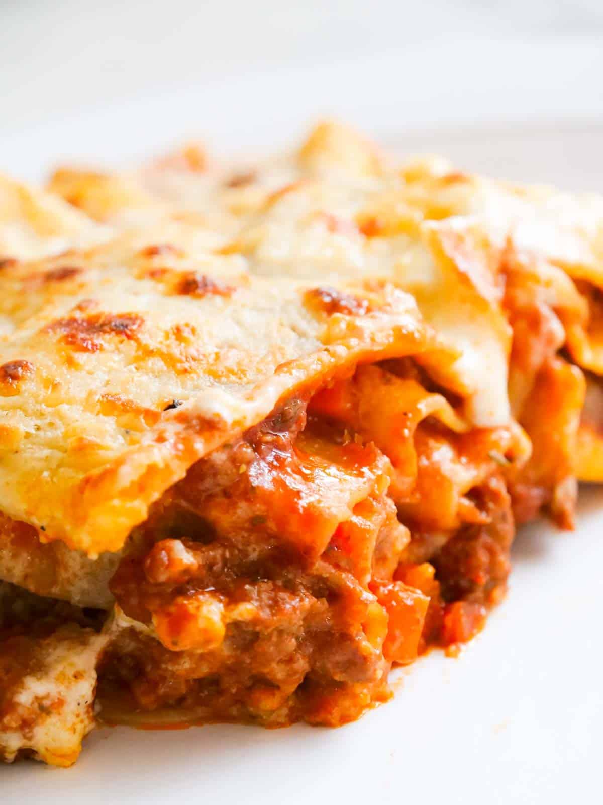 Close up of lasagne layers on a white natural Canvas Denby plate.