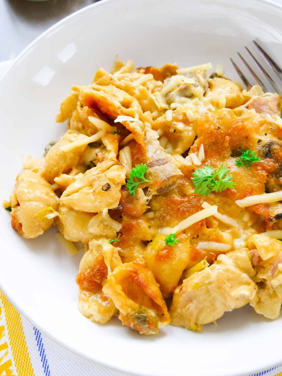 Close up of luxurious cheesy pasta bake in a Denby bowl and a sprinkle of cheese and fresh parsley