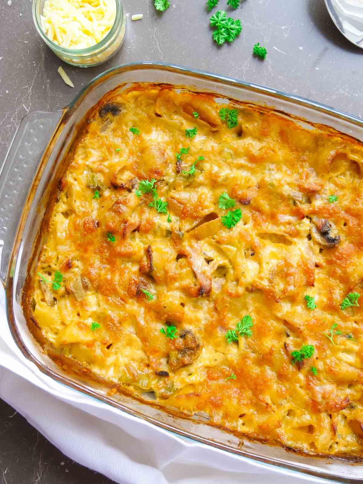 Freshly baked recipe for cheesy pasta in a large Pyrex casserole dish on a brown marble worktop