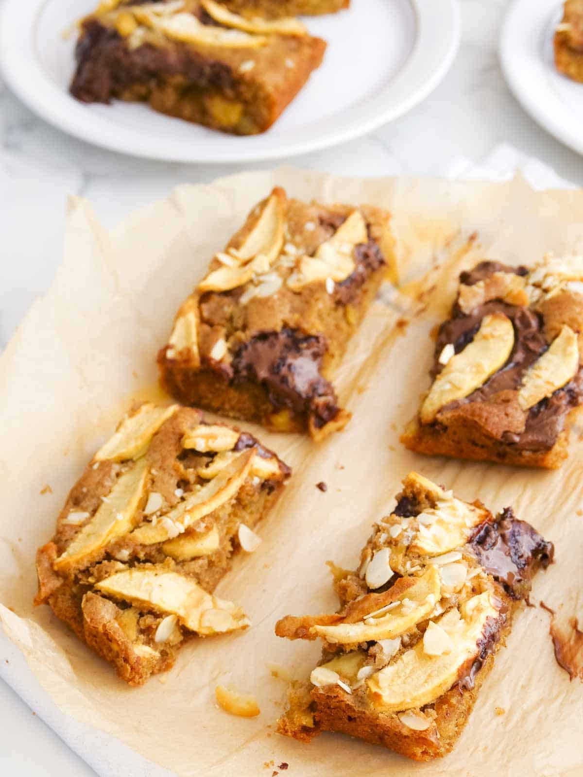 Close up slices of apple topped cinnamon cake on baking paper