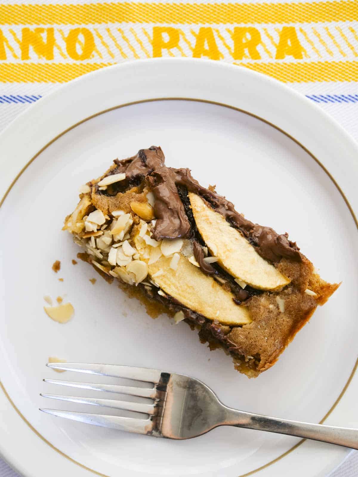 Slice of moist apple cake with chocolate and cinnamon on a white Denby plate