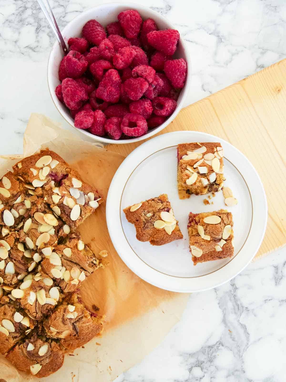 Divine chocolate raspberry and almond squares serves on a white Denby plate and wooden serving platter