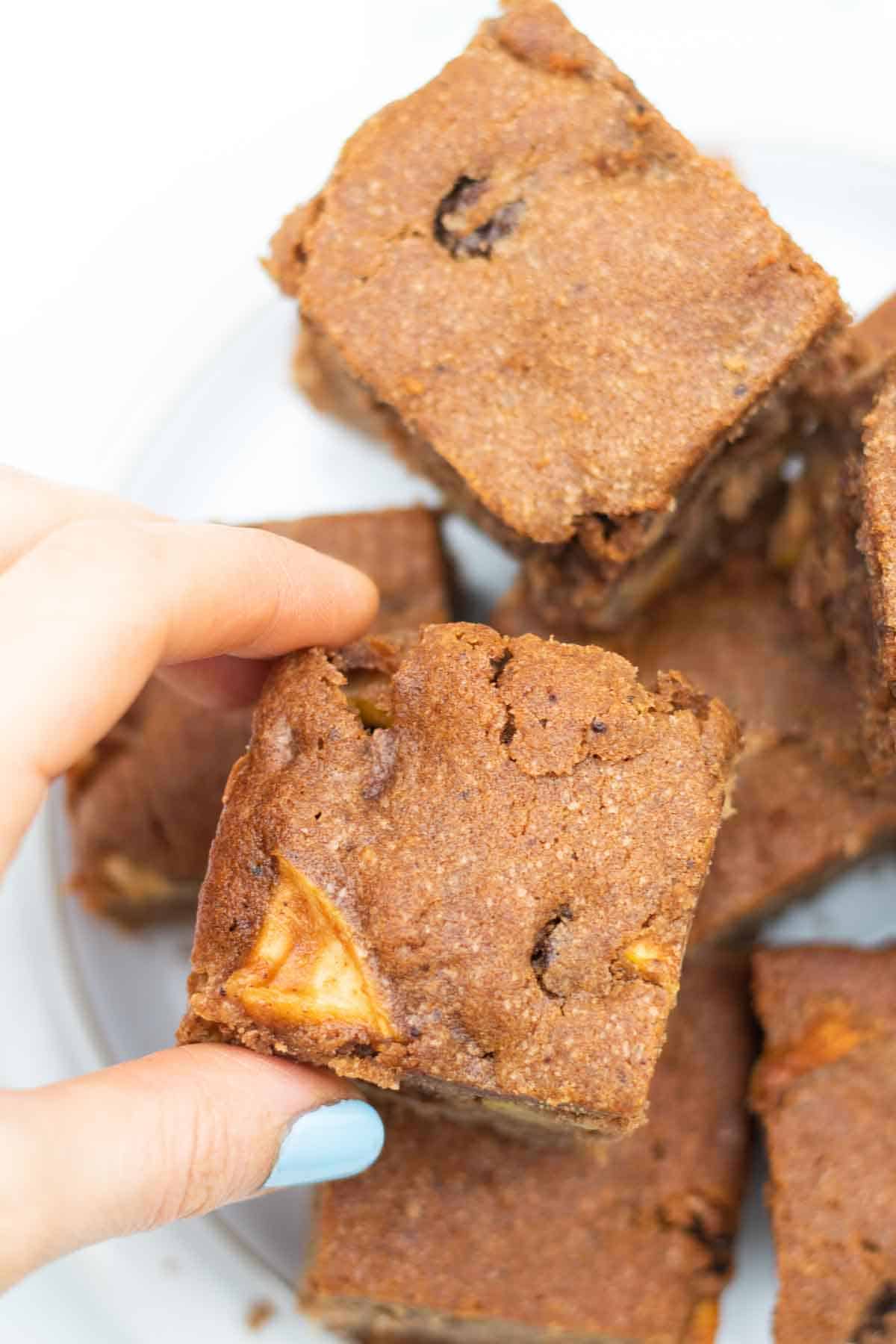 Picking up a piece of apple raisin cake baked with cocoa powder and ground cinnamon