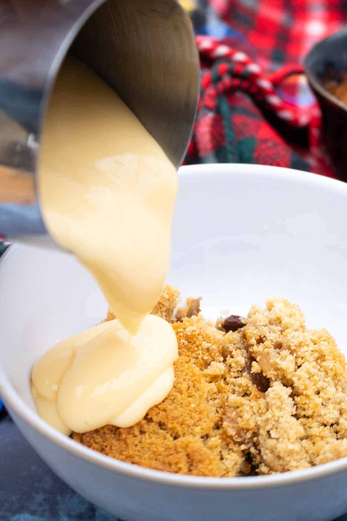 Pouring custard into a bowl and apple and mincemeat crumble