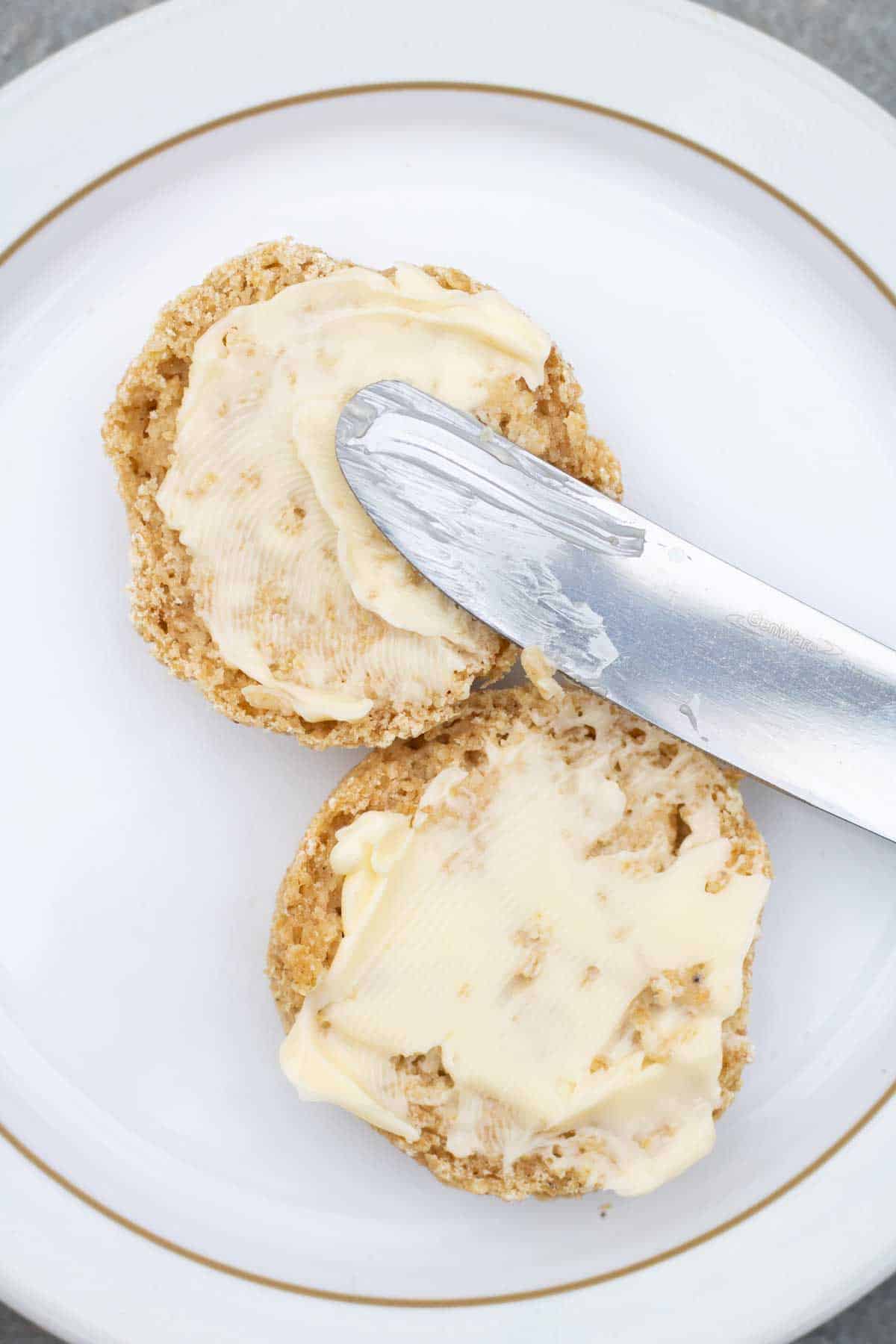 Buttering a oatmeal scone before putting jam on