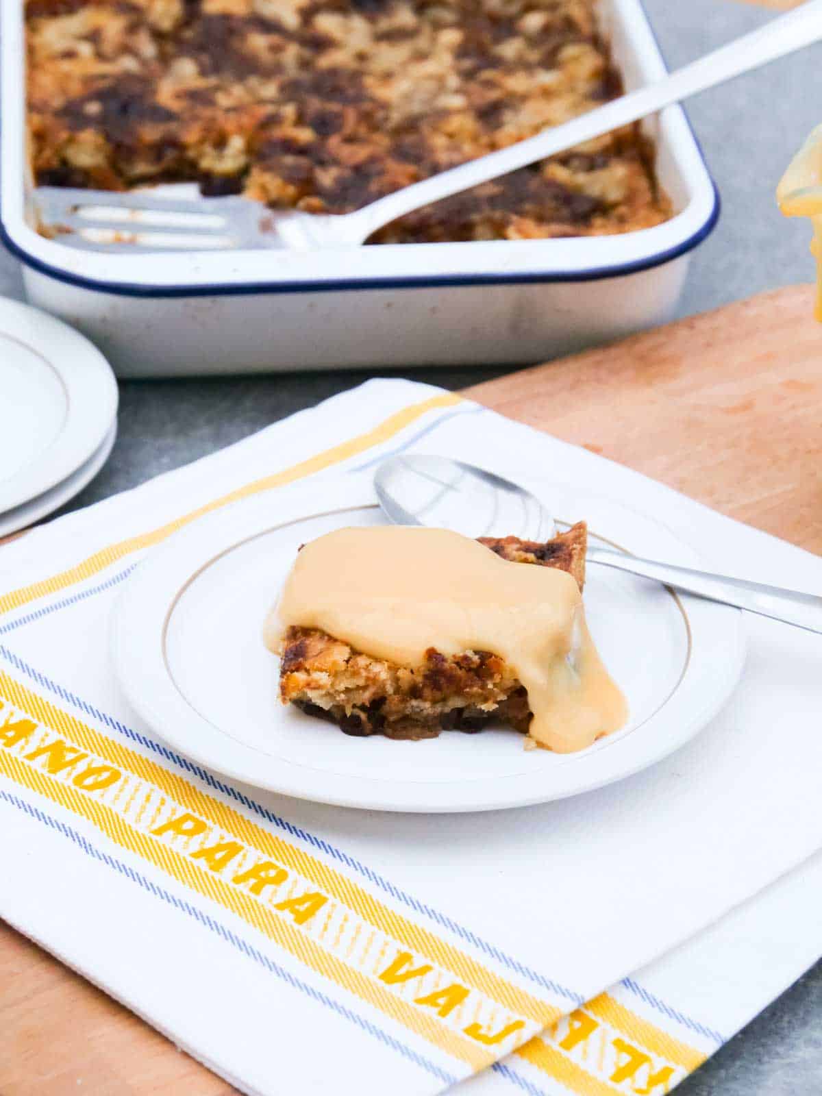Custard poured on top of apple spice dump cake on a small white plate