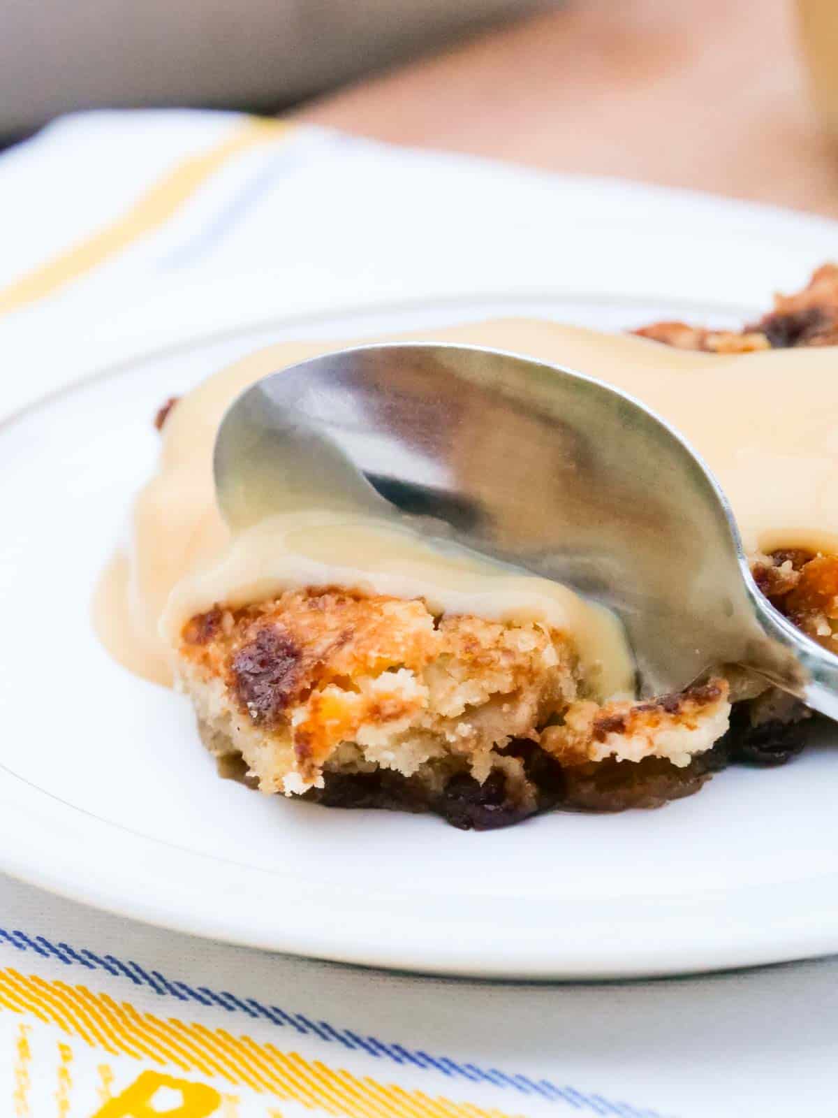 Eating apple dump cake with custard using a spoon
