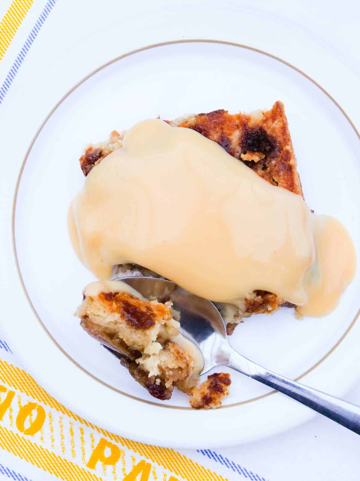 apple and raisin dump cake on a small white plate with custard