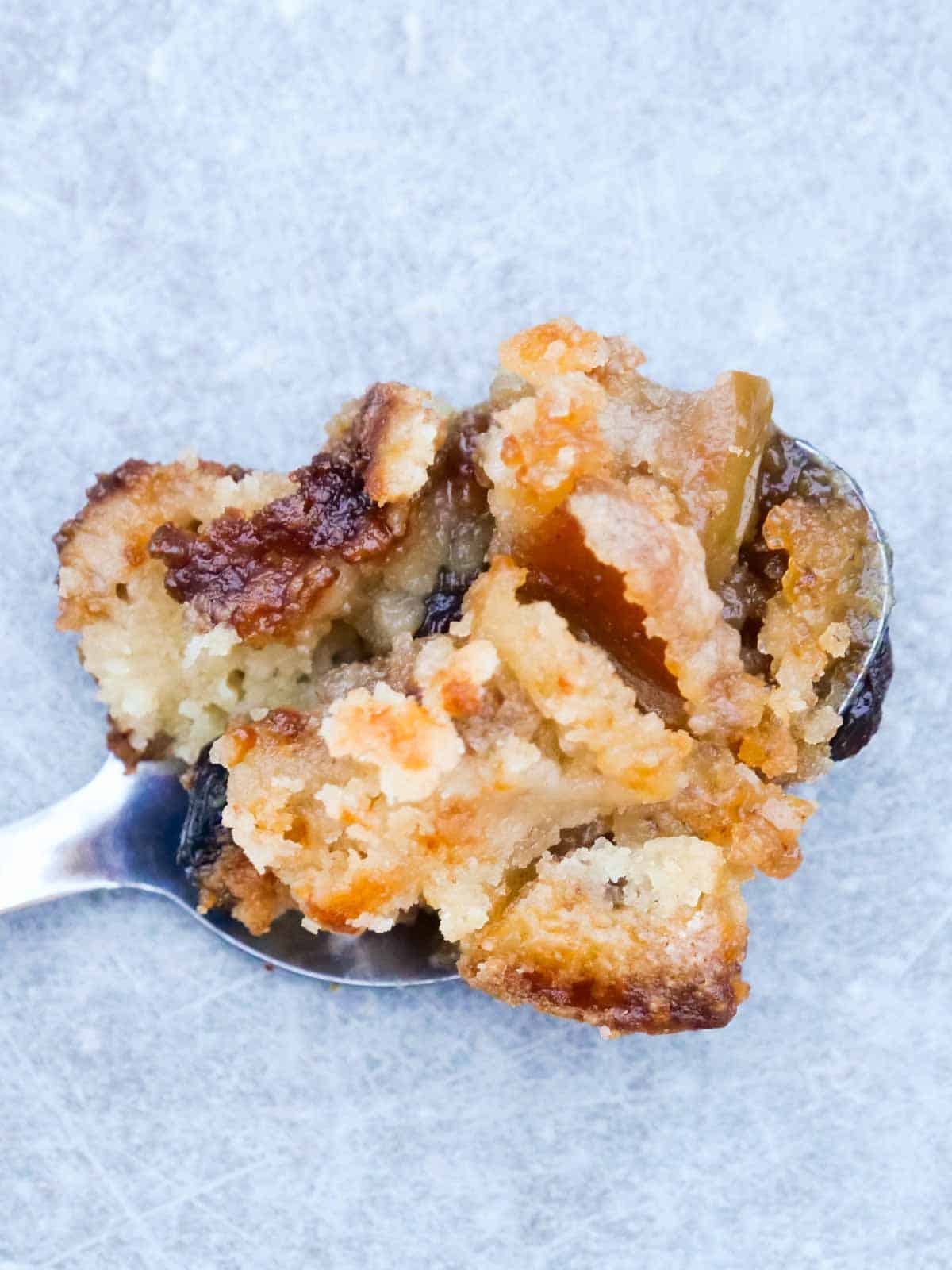 Large spoon oozing with salted caramel and homemade toffee pieces on an apple dump cake