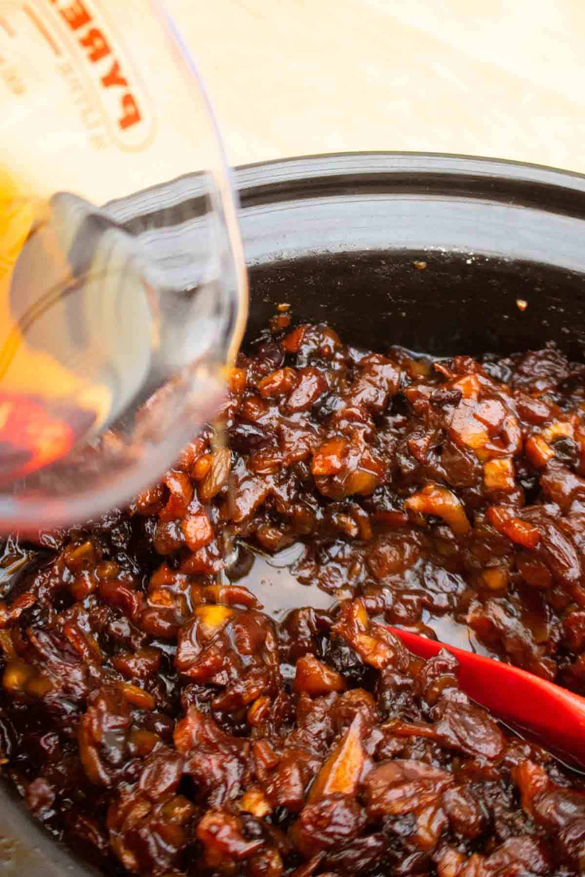 Pouring French brandy into cooked mincemeat after 6 hours in a slow cooker