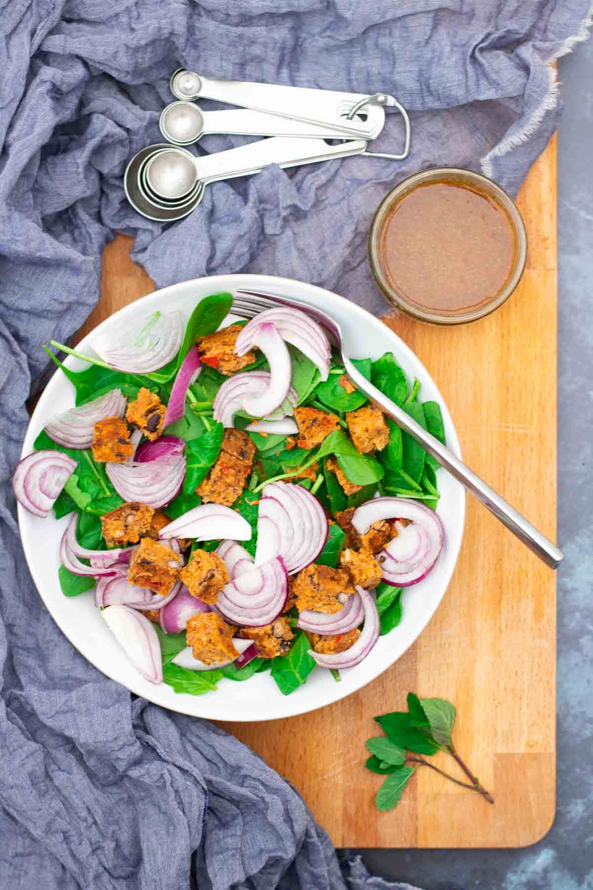 Plain vegan salad in a large white bowl before a dressing with tahini and maple syrup is poured on top