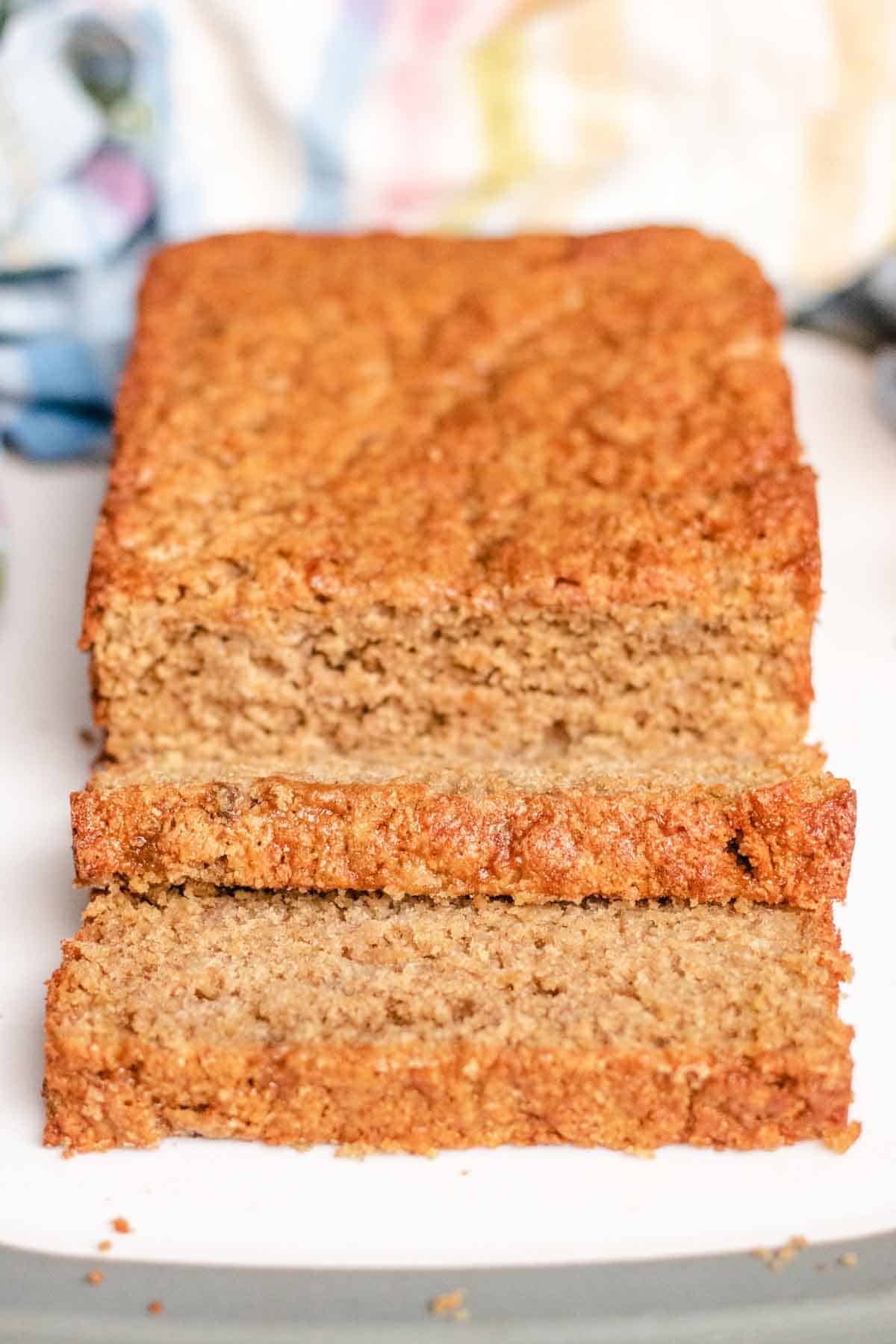 Close up of a golden banana bread with oat flour on white chopping board