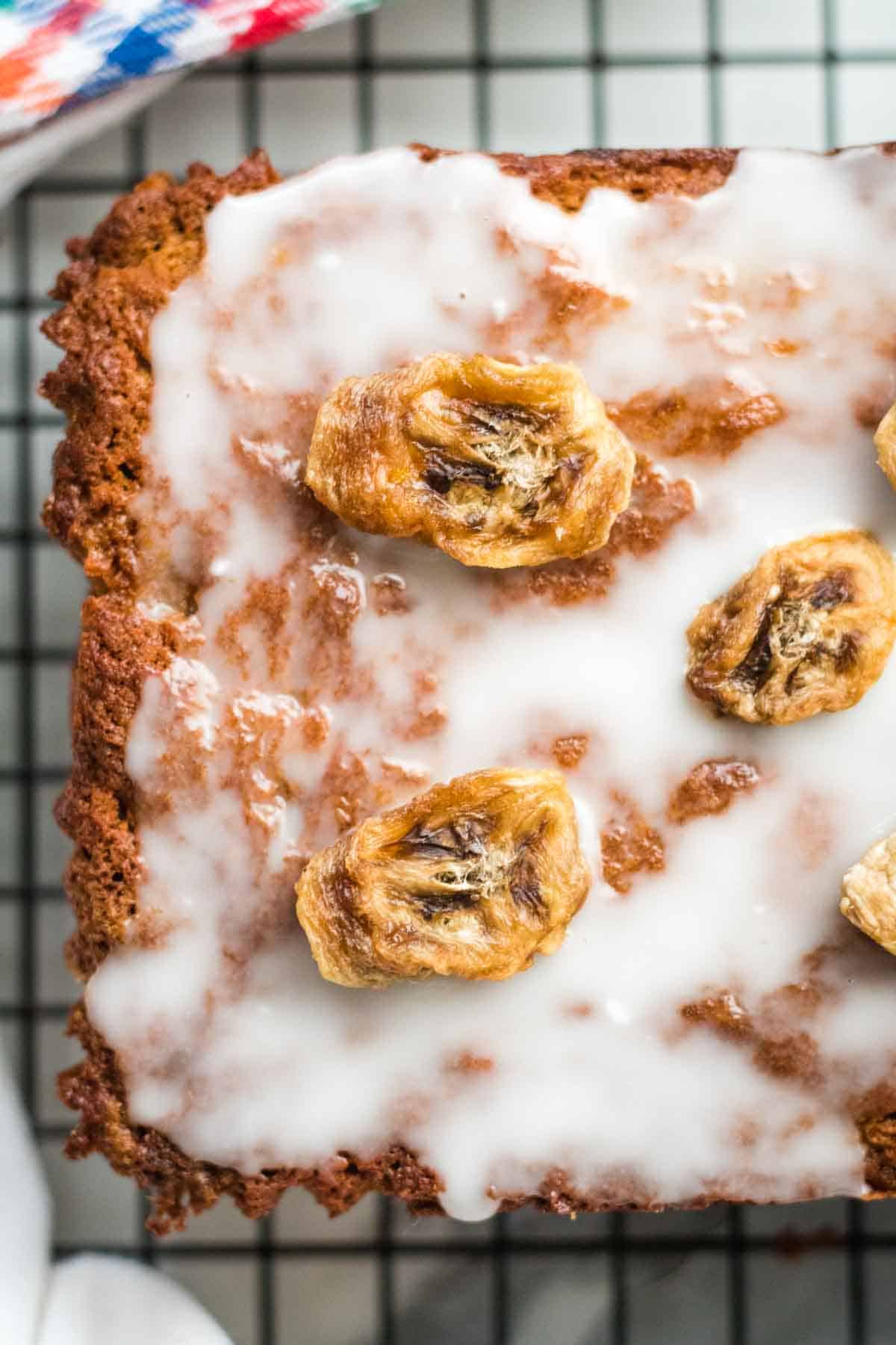 Close up of dehydrated banana chips on an iced banana bread