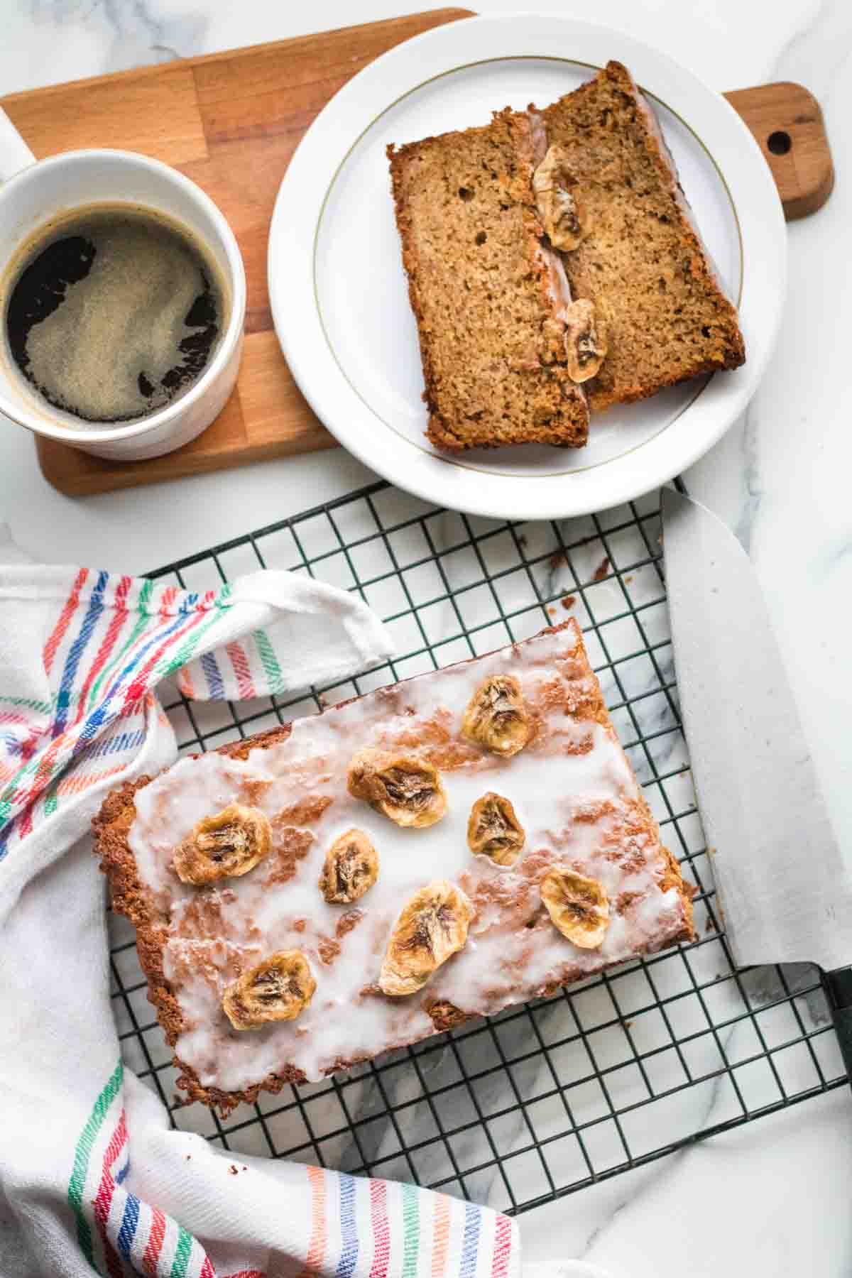 Coffee and banana bread slices on a white marble kitchen worktop