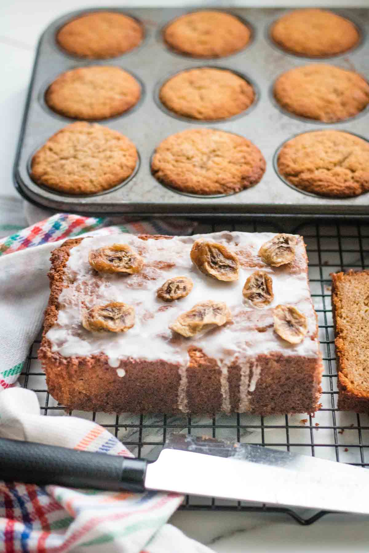 buckwheat flour banana muffins in a 12 cupcake tray alongside a loaf bread with icing and banana chips using the same cake mix
