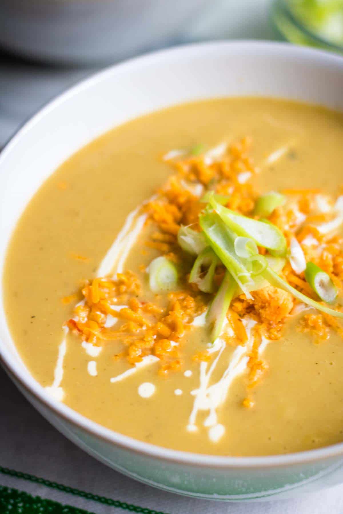 Close up of sliced onions, vegan grated cheese and cream on a keto soup