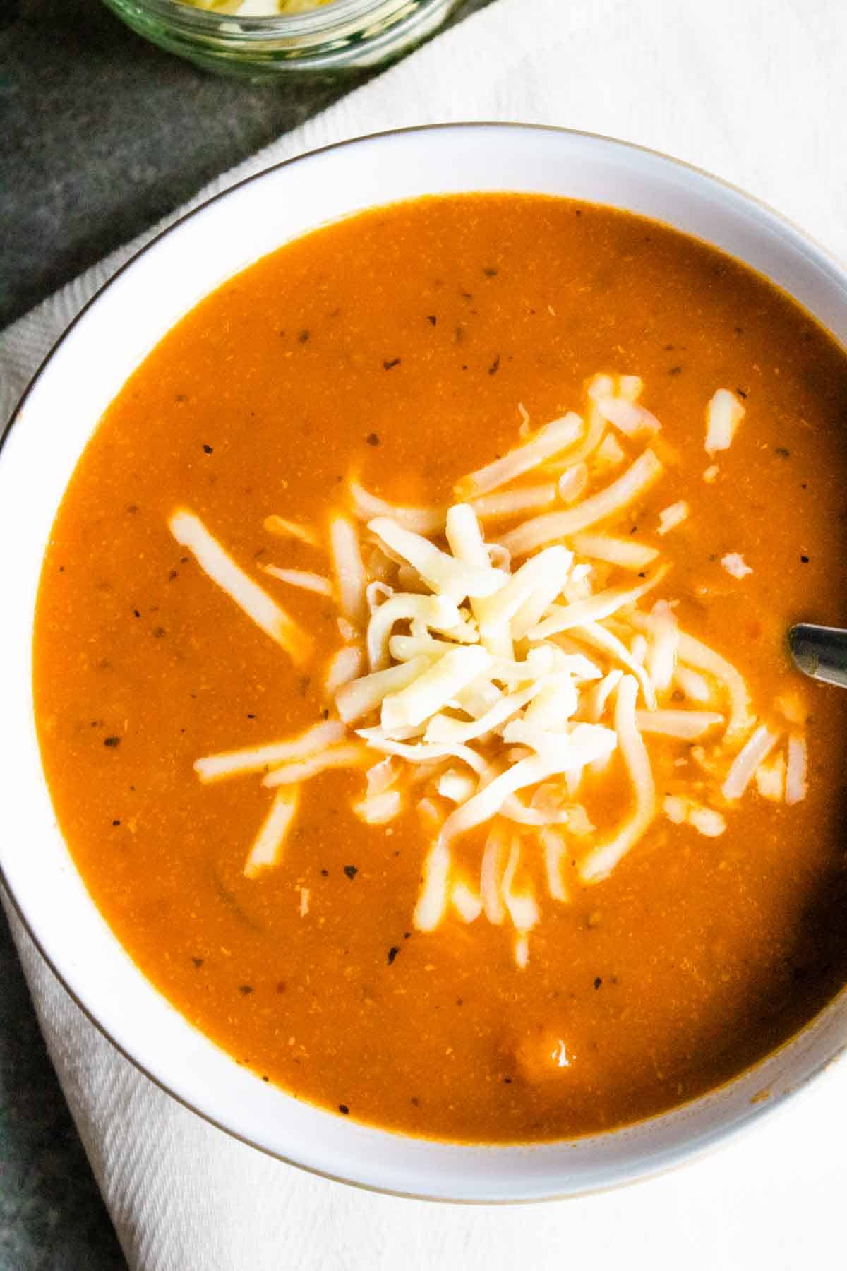 Close up of a vegan creamy chunky tomato soup topped with grated cheese