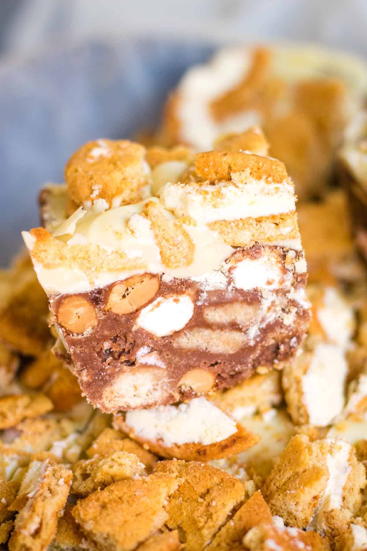 A close up a of square from a Christmas ourmet rocky road recipe - full of nuts, biscuits, orange and while chocolate