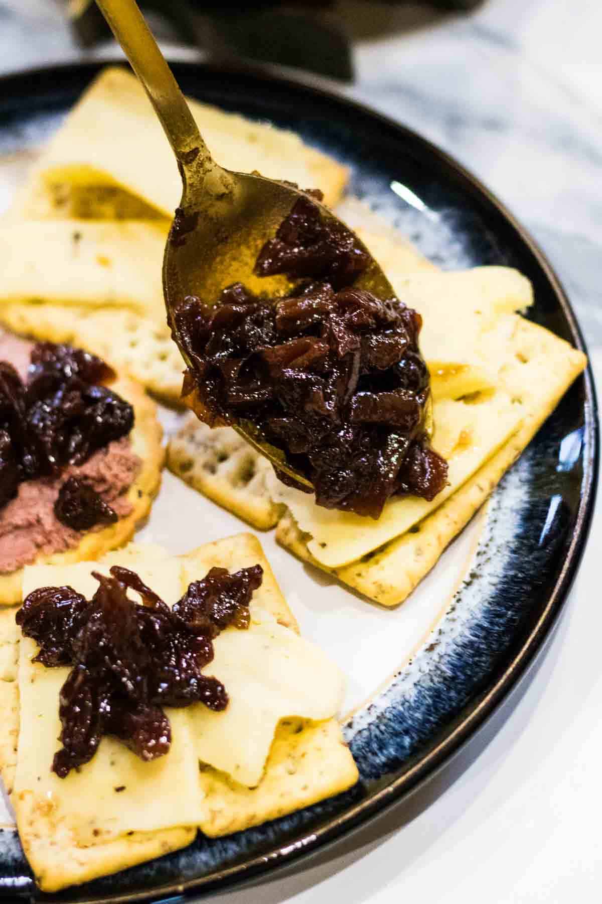slow cooker red cabbage chutney being spooned onto cheese and crackers