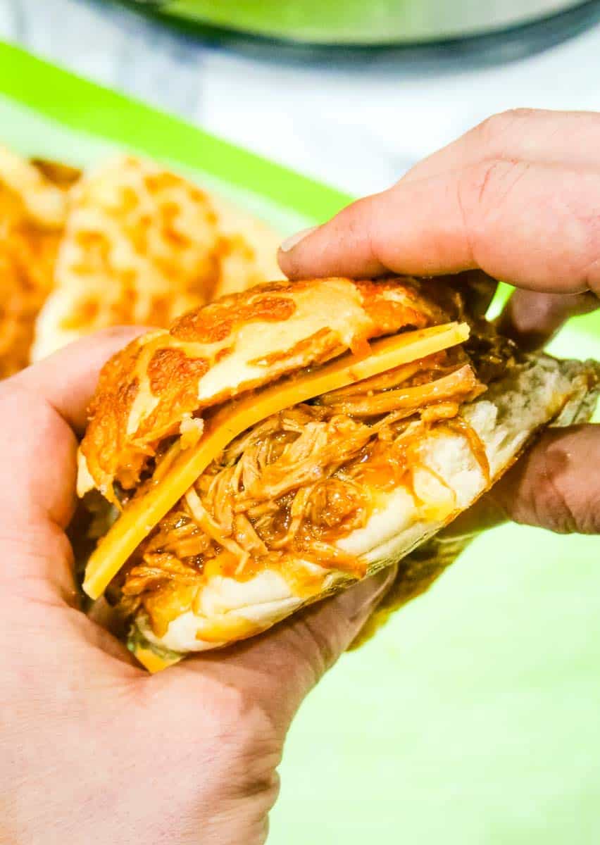 Close up of someone holding a pulled pork slider with cheese