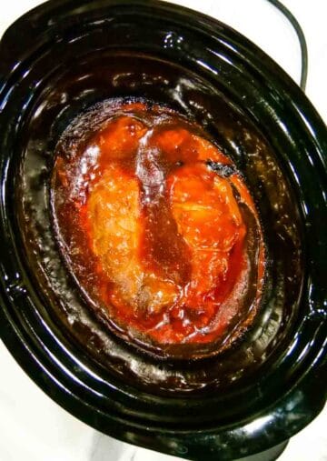 Slow cooker full of cooked pork in BBQ sauce
