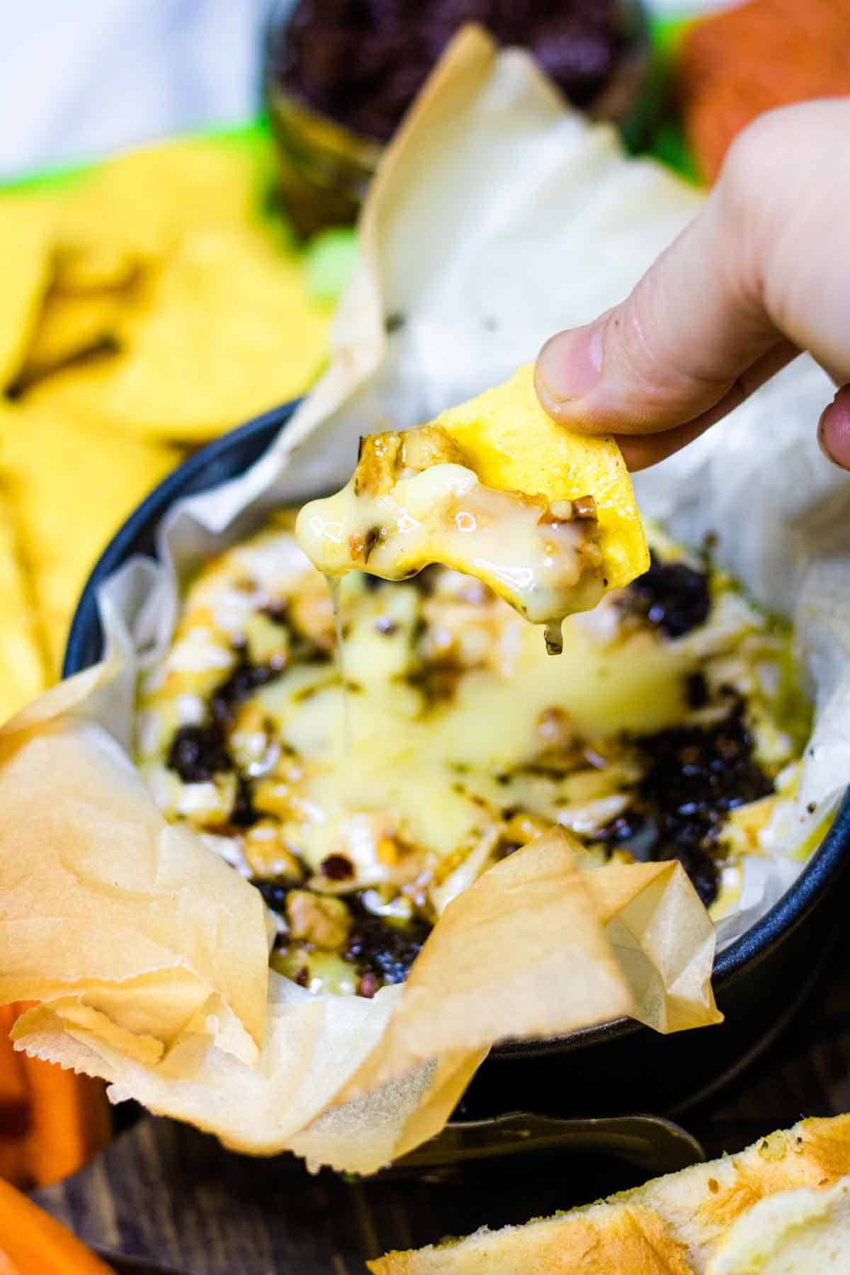 Close up of a nacho being dipped into melted cheese