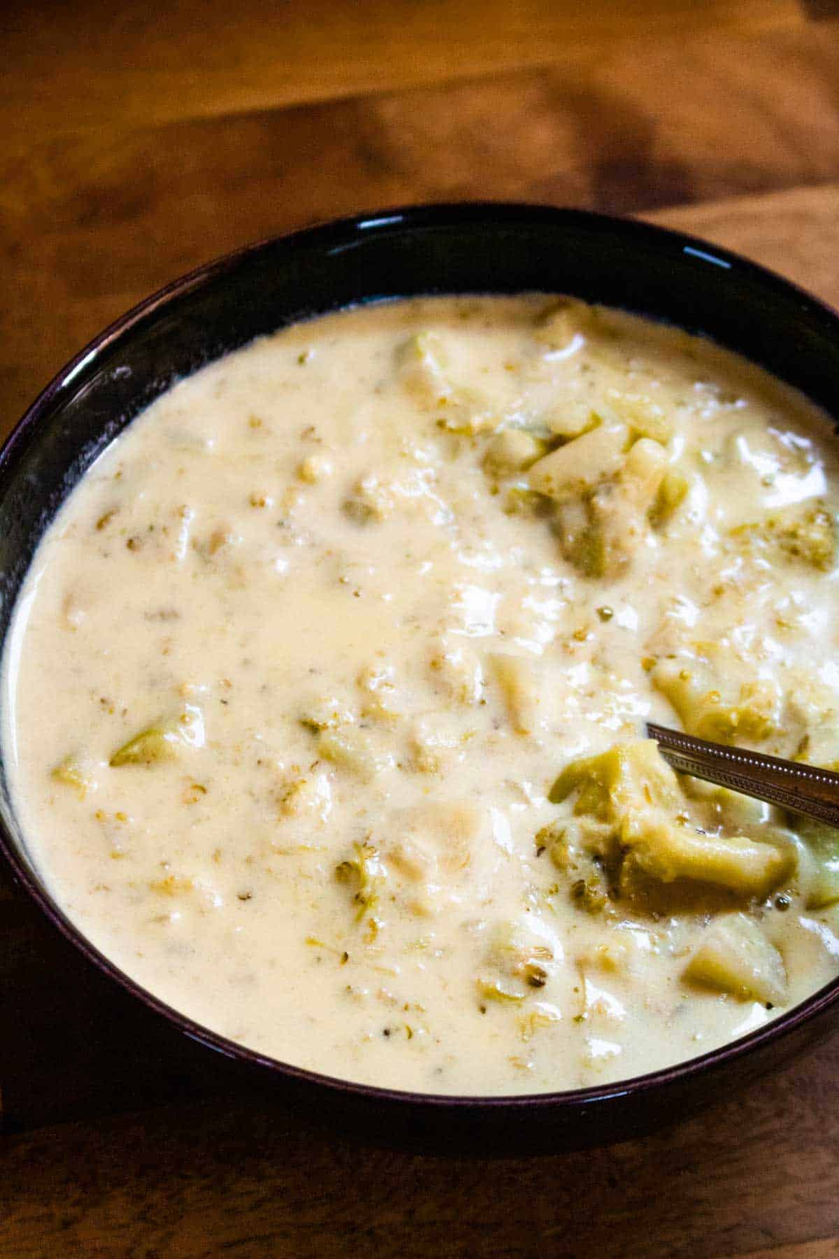 close up of broccoli and cheese soup without potato in black bowl