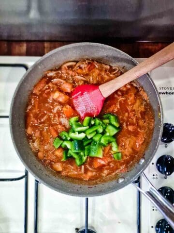 tomatoes and green bell peppers being cooked in a pot on the hob