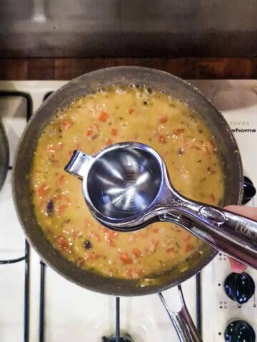 lemon juice being squeezed into carrot lentil soup