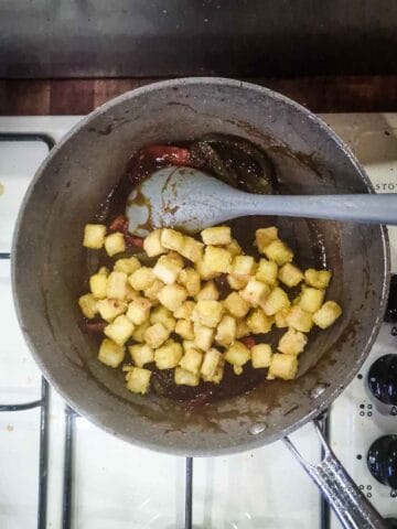 crisped tofu being stirred back into a frying pan with sweet chili sauce