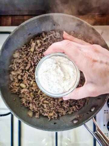 Adding cornflour to mincemeat in a pan