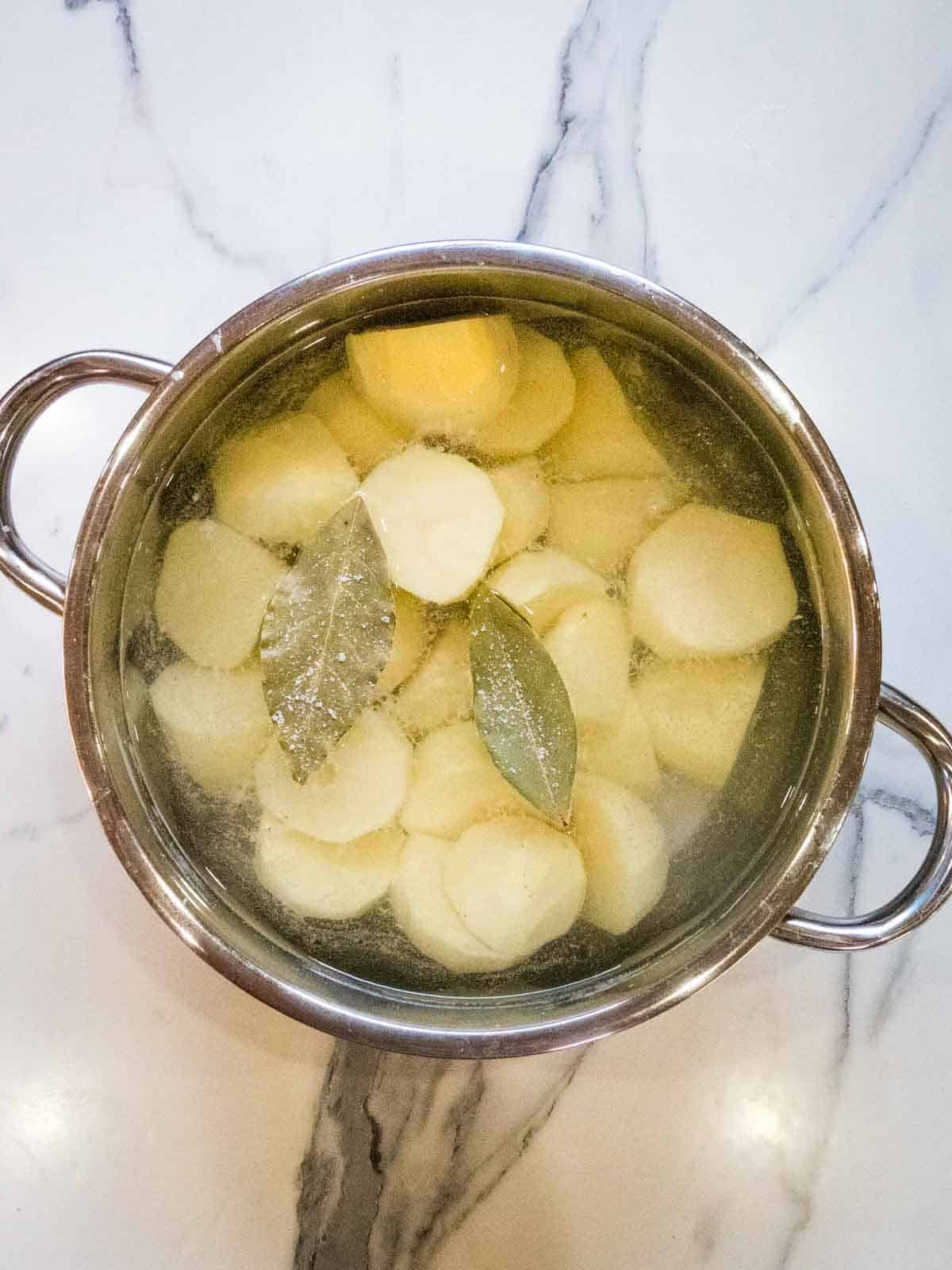 chopped potatoes in a pan with bay leaves