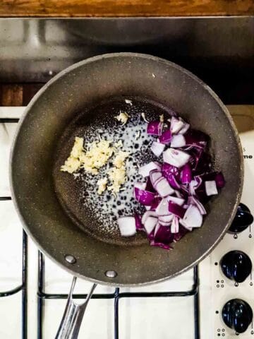 onions and garlic being fried in a large pan