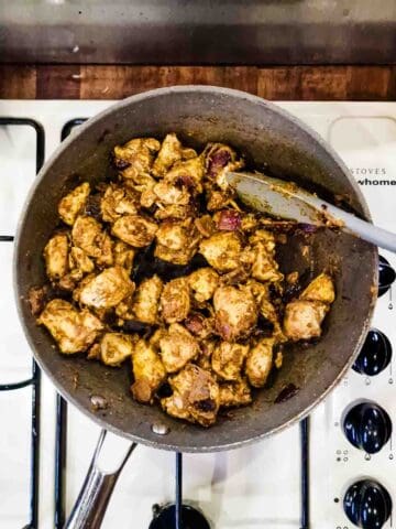 chicken chunks being coated with Indian curry spice