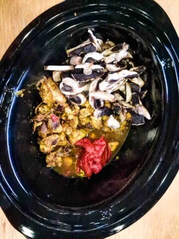 healthy chicken curry ingredients in a black slow cooker pot
