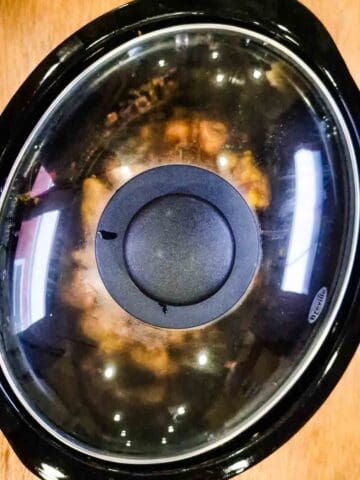 Lid on a slow cooker and food being cooked