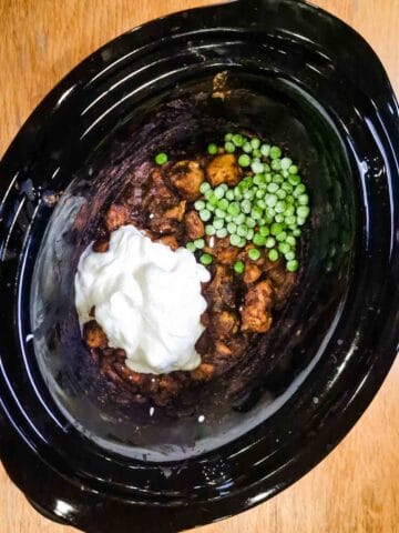 Cream and fresh peas added to a slow cooker pot after cooking