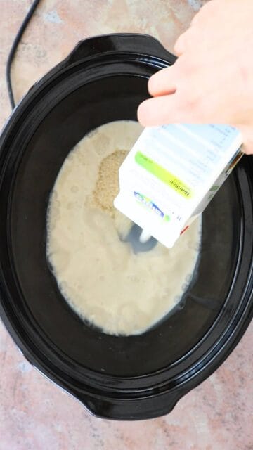 milk being poured into a slow cooker with pudding rice