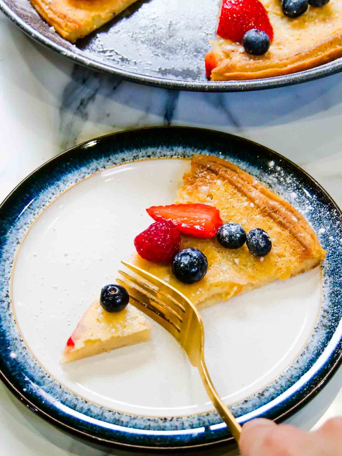 Cutting a slice of German pancake with a gold fork