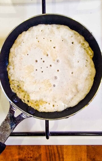 pancake batter bubbling in a frying pan